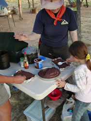 Frosting a freshly baked solar oven chocolate cake.